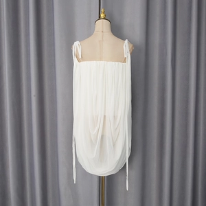 Detail view of white pleated camisole with shoulder ties and semi-sheer fabric texture