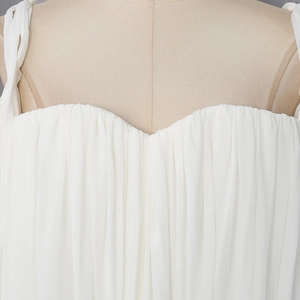Detail of white pleated camisole top featuring thin straps and sweetheart neckline texture
