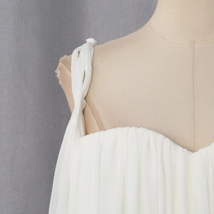 Detailed view of white chiffon top featuring gathered pleats and decorative shoulder ties