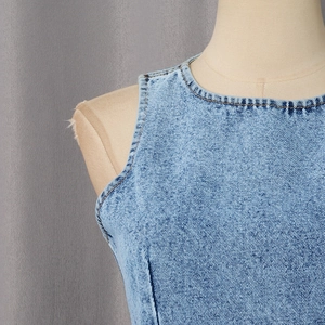 Detail of light blue denim sleeveless top with visible twill texture and washed finish