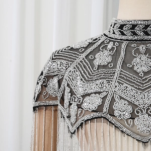 Detailed macro shot of vintage flower beadwork and long tassels on black mesh shawl