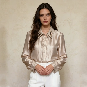 Close-up of champagne satin shirt collar with intricate black and brown gemstone embroidery