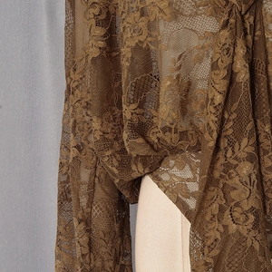 Gros plan du tissu d'un body en dentelle café noir avec motifs floraux ajourés