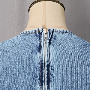 Detail of light blue denim top with hidden metal zipper and classic yellow stitching