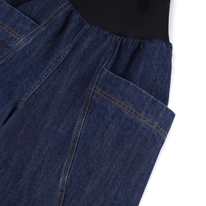Detail of high waist maternity jeans with black elastic band and orange stitching