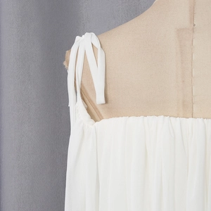 Close-up of white ruched camisole top featuring delicate adjustable shoulder tie straps