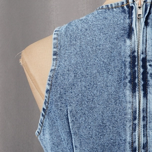 Close-up of light blue denim vest back with long silver metal zipper and contrast stitching