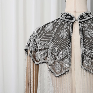 Close-up detail of vintage beaded shawl featuring silver fringe and floral sequin embroidery