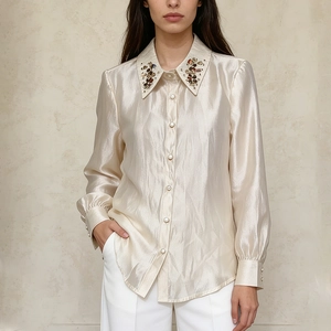 Detail view of champagne satin shirt with multi-colored gemstone embellishments on collar