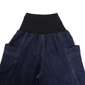 Detail of high waist elastic knit waistband and large side pockets on blue denim jeans