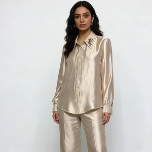 Close-up detail of champagne satin shirt showing beaded collar and shiny fabric texture