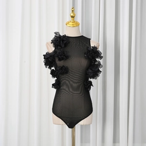 Detail of black mesh bodysuit featuring 3D floral appliques and sheer high-neck design