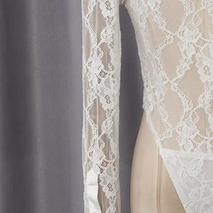 Detail of white long sleeve bodysuit featuring delicate floral lace and satin buttoned cuffs