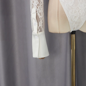 Detailed view of white floral lace sleeves and double-buttoned cuffs on the bodysuit