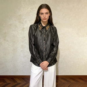 Detail of black satin shirt with rhinestone embellishments on the collar and buttoned cuffs