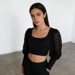 Detail of elegant black lace crop top featuring puff sleeves and intricate floral patterns