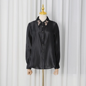 Detailed view of pink floral embroidery and pearl accents on a black satin shirt collar