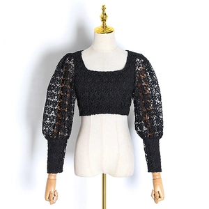 Detailed view of the sheer black floral lace pattern on a cropped puff sleeve shirt