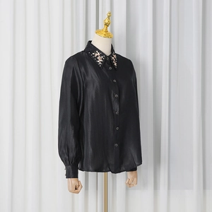Close-up of black satin shirt collar with pink floral sequin and bead details