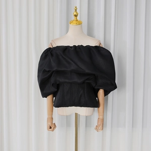 Detail view of black off-shoulder corset top with voluminous puff sleeves and satin finish
