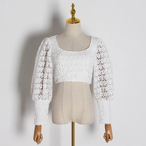 Detail of white lace crop top with elegant square neckline and puff sleeve texture