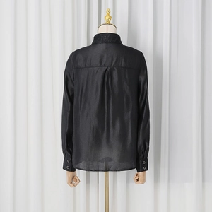 Detail of black satin shirt back showing sleek pleated design and smooth silk texture