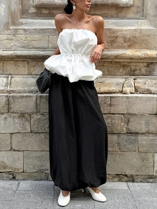 Haut à basque blanc sans bretelles et pantalon large noir pour un look de rue très élégant