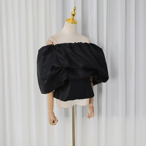 Detail of black off-shoulder corset top with voluminous puff sleeves and cinched waistline