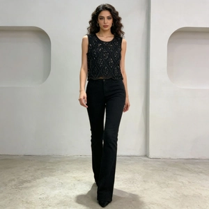 Détail du gilet noir orné de perles élégantes porté avec un pantalon raffiné