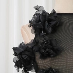 Detail of 3D handmade floral appliques on sheer black mesh fabric for a slim jumpsuit
