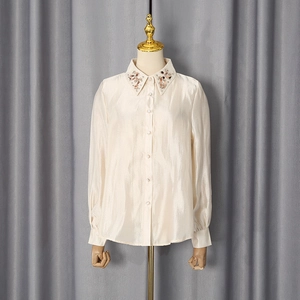 Detail of beaded floral embroidery on collar of cream satin long sleeve blouse