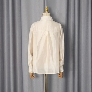 Detailed back view of a loose satin shirt featuring shoulder yoke and central box pleat