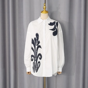 Detailed view of white cotton shirt featuring elegant dark sequin embroidery on shoulder