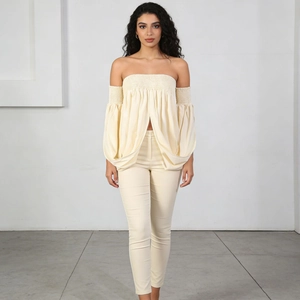 Detail of elegant cream off-shoulder blouse with pleated sleeves and matching trousers