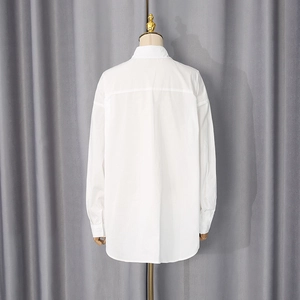 Rear view of a white oversized cotton shirt with a curved hem on a mannequin