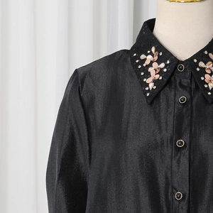Detailed close-up of a black satin shirt featuring pink sequin flowers and crystal beads