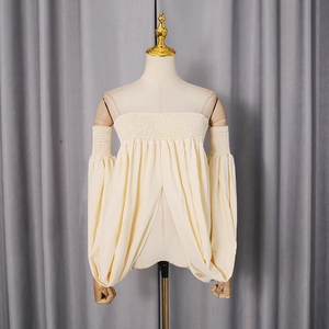 Detail of off-white off-shoulder top showing intricate smocking and lantern sleeve texture