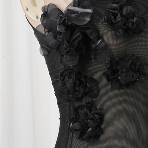 Detail of sheer black mesh fabric featuring hand-sewn 3D floral appliqués and textures