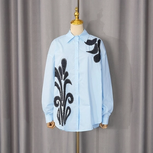 Detailed view of light blue shirt featuring intricate black sequin floral embroidery