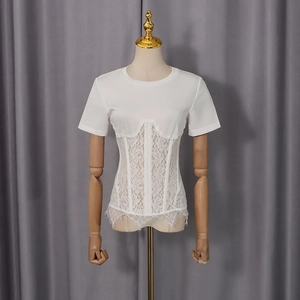 Dettaglio di t-shirt bianca attillata con vita in pizzo floreale e bordo in pizzo a ciglia
