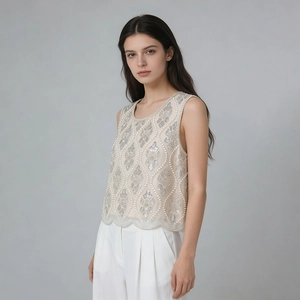 Détail de la broderie de perles de luxe et de l'ourlet ondulé sur le haut de couleur champagne