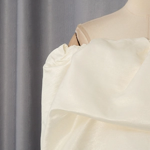 Detailed close-up of cream off-shoulder corset top showing shiny satin fabric texture