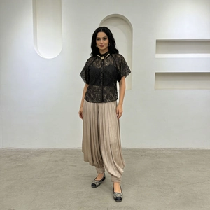 Gros plan sur un pantalon sarouel en satin plissé champagne et haut en dentelle noire