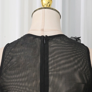 Detail of sheer black mesh bodysuit featuring a hidden back zipper and 3D floral accents