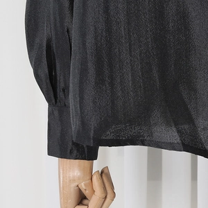 Detail of black rhinestone shirt cuff and silky fabric texture on white background