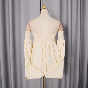 Detail of cream smocked back top with elegant puff sleeves on a mannequin display