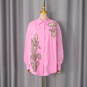 Close-up of pink long-sleeve shirt featuring dark sequin leaf details on the shoulder