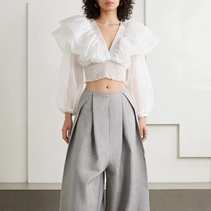Dettaglio del crop top in mesh bianco con maniche in organza a balze e vita a punto fumo