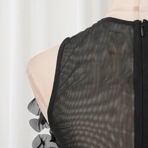 Macro detail of black mesh bodysuit with invisible back zipper and floral fabric accents