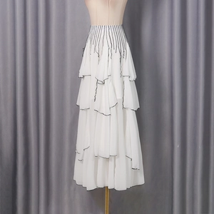 Close-up of white layered mesh midi skirt with elegant black piping and pleated waist